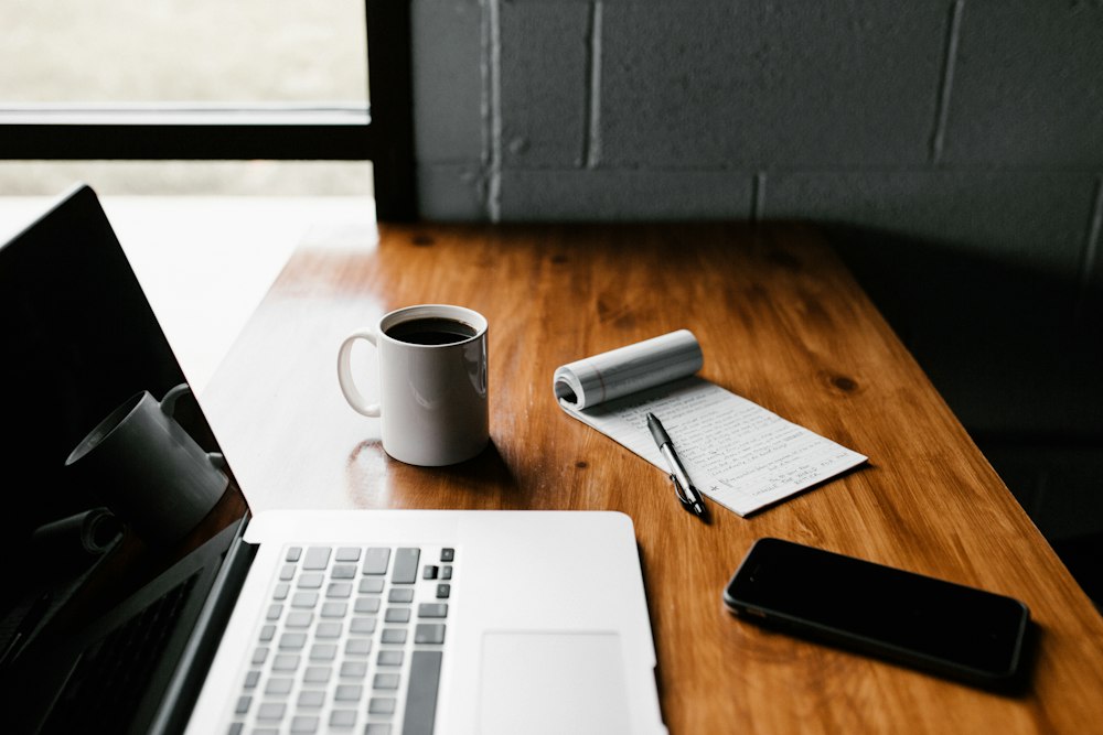 A laptop and notebook on a work desk